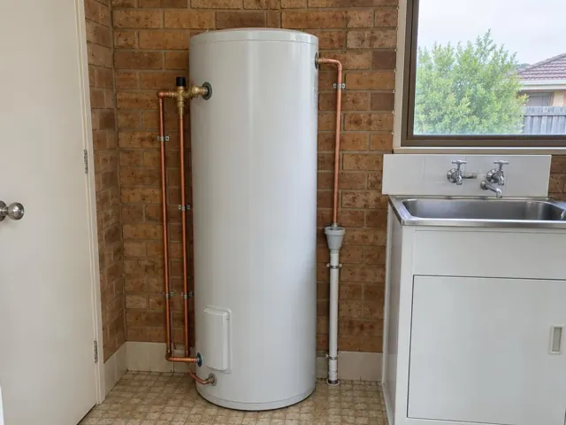 Indoor hot water cylinder beside a laundry sink and brick wall in Forestville